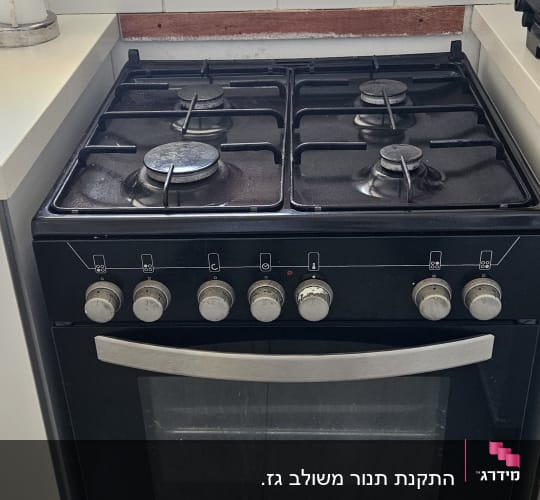 תנור גז שחור עם ארבעה מבערים וכפתורים